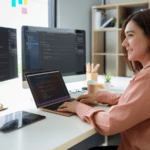 Female data analyst working with multiple monitors displaying code, symbolizing data literacy in the professional sector.
